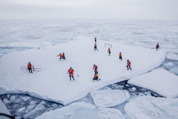 KV Svalbard's crew play soccer as they are protected from polar bears by armed guards in the arctic environment in the sea around Greenland